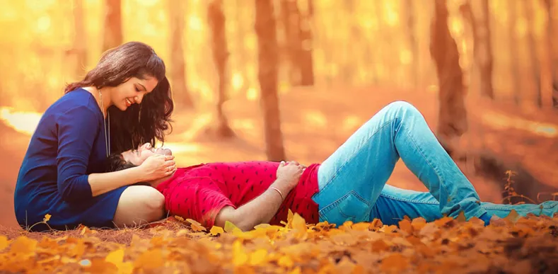 Couple in love resting in autumn park with fallen leaves